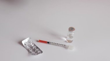 Bir kadın beyaz tabletler elinde, gösterilen blister, siringe boş ve beyaz masa arka plan üzerinde şişe