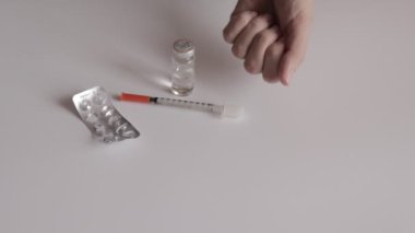 Bir kadın elinde beyaz tabletler gösterilen ve aşağı - boş blister, siringe ve flakon beyaz masa arka plan üzerine atmak