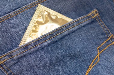 Condom in blue jeans pocket, contraception and sexual health concept.