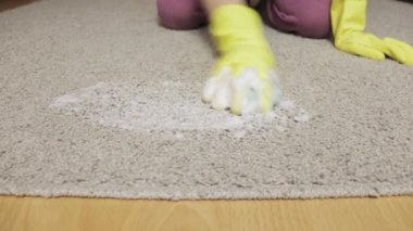 Kadın sarı lastik eldiven bir sünger ve köpük ile halı yıkama