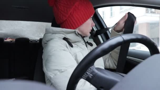 妇女在冬天的衣服和橙色针织帽子系安全带在汽车里 准备驾驶 — 图库视频影像