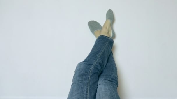 Jambes de femme en jeans et chaussettes se détendre contre un mur blanc avec espace de copie — Video