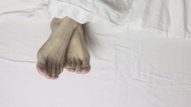 Jambes de femme pieds couchés au lit, vue sur le dessus, réveil matinal et détente — Video