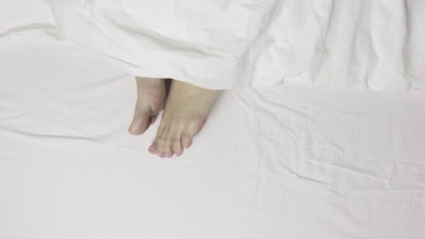 Jambes de femme pieds couchés au lit, vue sur le dessus, réveil matinal et détente — Video