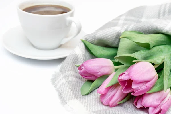 Woman working desk with coffee mug, notebook and spring pink bouquet of tulip flowers, feminine flat lay style.