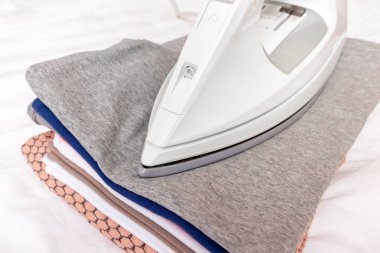 Modern elektrikli beyaz demir elbise yığını üzerinde yakın çekim - Ütü, Çamaşırhane ve ev işleri kavramı.