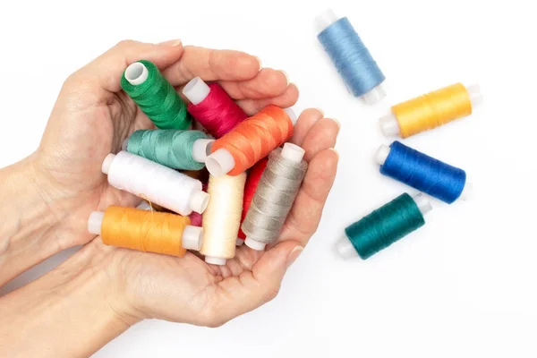 Mani che tengono un sacco di bobine colorate di filo da vicino, sfondo bianco hobby e fai da te come ebroidery sartoria e cucito — Foto Stock