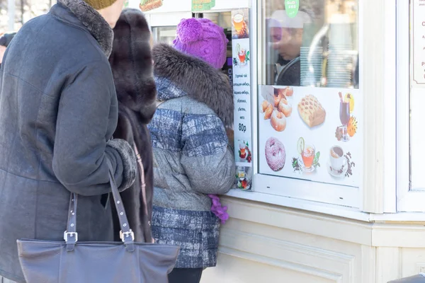 MOSCÚ, RUSIA - 02 DE MARZO DE 2019: La gente que compra comida rápida en la calle y bebidas calientes en el puesto durante el paseo en un parque de la ciudad en invierno, comiendo comida rápida sobre la marcha — Foto de Stock