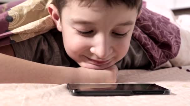 Chłopiec Leżących Łóżku Domu Relaks Uśmiechając Się Oglądać Wideo Smartphone — Wideo stockowe