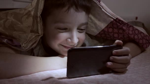 Ragazzo Sdraiato Letto Casa Rilassarsi Sorridere Guardare Video Smartphone Buio — Video Stock