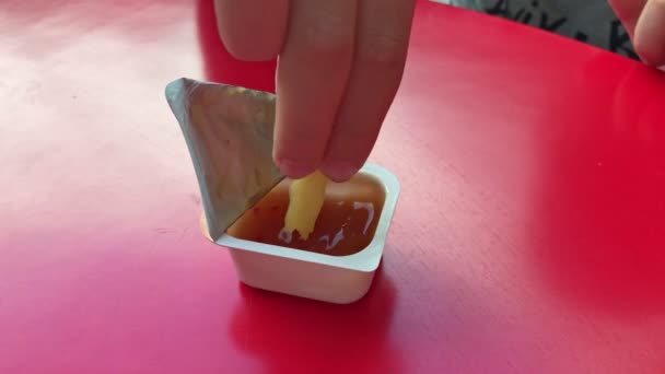 Vídeo en cámara lenta de las manos de los niños sumergen papas fritas en un recipiente desechable de plástico con salsa, de cerca — Vídeo de stock