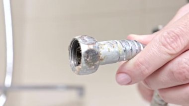 Kırık leaky Duş Hortum kadın elinde kireç kaplı bir küvet musluk yakın çekim