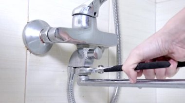 Küvet musluk bir leaky duş su musluk, sıhhi tesisat onarım ve DIY kavramı üzerinde bir somun gevşeterek reparing