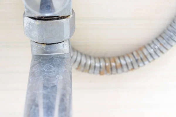 Detail of dirty calcified shower mixer tap and shower hose, faucet with limescale or lime scale on it, close up