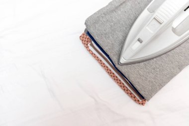 Modern elektrikli demir ve bir kopya alanı ile beyaz arka plan üzerinde elbise yığını