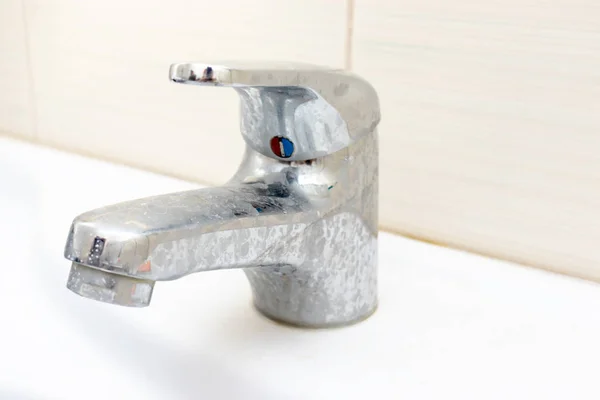 Dirty faucet with limescale, calcified water tap with lime scale on washbowl in bathroom