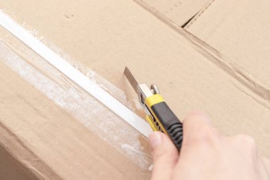 Bir karton kutu ile yeni mobilya yeni evine taşınıyor ve yeni mobilya satın alma inşaat veya office bıçakla - unboxing