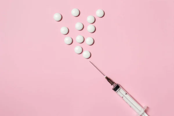 Siringa con compresse bianche per iniezione e metafora di vaccinazione su fondo rosa, posa piatta, spazio per la copia — Foto Stock