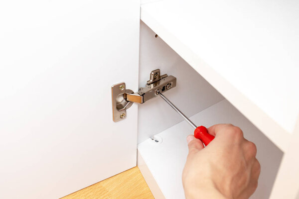 Adjustment of furniture doors using a screwdriver, assembling furniture concept