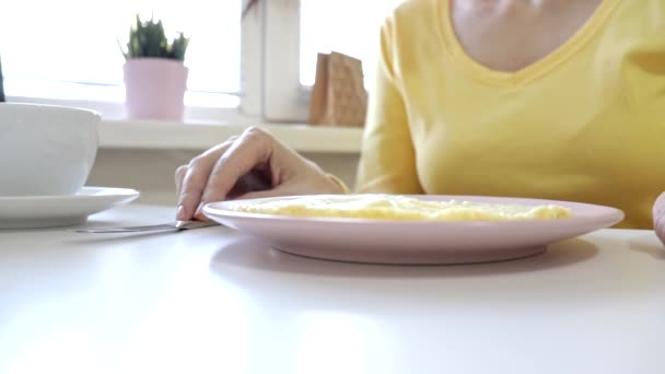 Femme assise à la table prête à manger une omelette et à boire du café ou du thé pour le petit déjeuner à la maison ou au restaurant, la vapeur provient de la nourriture — Video