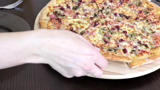 Vrouw zitten door de tabel en het nemen van een stukje heerlijke pizza, zetten het op de plaat — Stockvideo