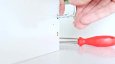 Bir tornavida kullanarak yeni beyaz çekmece montaj bir kişinin görünümü kadar yakın, bir onaltılık bir allen anahtarıyla sıkıştırın