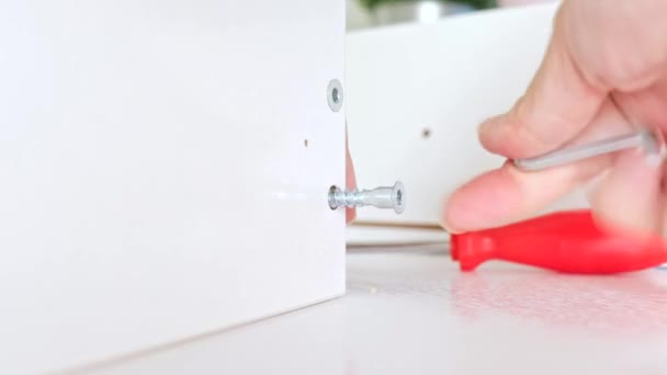 Vista de cerca de una persona montando un nuevo cajón blanco usando un destornillador, apriete un tornillo con una llave Allen hexagonal — Vídeo de stock