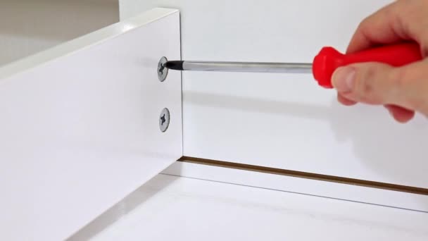Nahaufnahme einer Person, die mit einem Schraubenzieher eine neue weiße Schublade zusammensetzt — Stockvideo