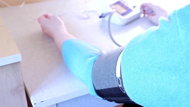 自宅で血圧を測定する年配の女性の手、眼圧計の袖口クローズアップ — ストック動画