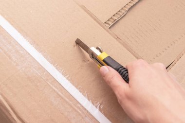 Bir karton kutu ile yeni mobilya yeni evine taşınıyor ve yeni mobilya satın alma inşaat veya office bıçakla - unboxing