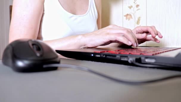 Mujer irreconocible usando un ratón y escribiendo algo en el teclado del ordenador portátil, enfoque superficial — Vídeos de Stock