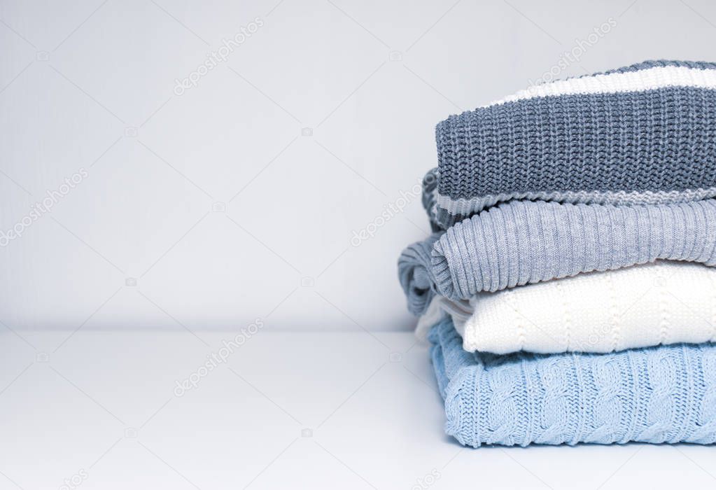 Stack of cozy comfortable homely clean washed knitted sweaters in pastel colors, laundry and washing clothes concept with copy space