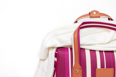 Kırmızı ve beyaz çizgili Bagaj çantası üzerinde bir örme kazak, beyaz arka plan, kopya alanı ile minimal seyahat kavramı