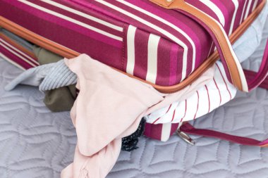 Kırmızı ve beyaz renkli çizgili bavul çanta dolu giysi-seyahat ve macera konsepti