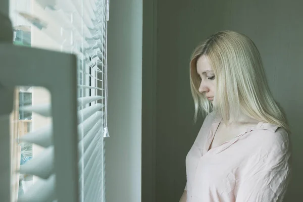 Triste donna sola apatica guardando attraverso una finestra a casa o in hotel, divorzio, depressione e apatia concetto — Foto Stock