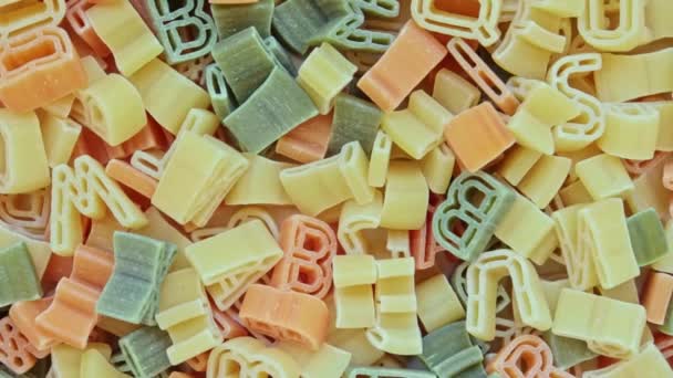 Alfabeto niños pasta italiana de diferentes colores primer plano textura rotación fondo — Vídeo de stock