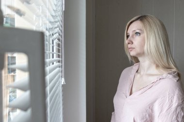 Üzgün kayıtsız yalnız kadın ev veya otel, boşanma, depresyon ve ilgisizlik kavramı bir pencereden bakarak