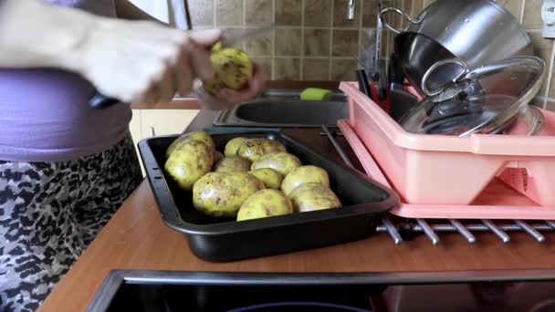 Uma mulher cortando batatas descascadas enquanto cozinha preparando a refeição — Vídeo de Stock