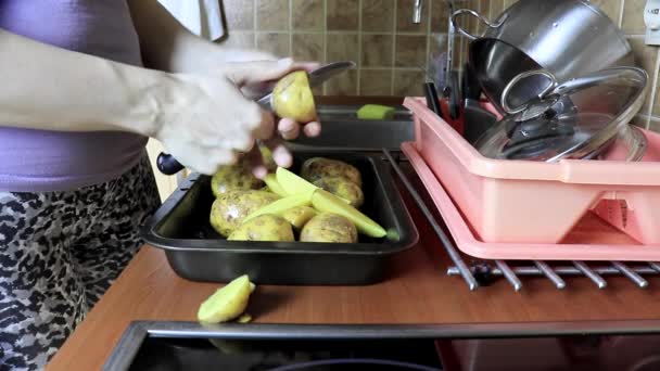 Жінка, що ріже нечисту картоплю під час приготування їжі — стокове відео