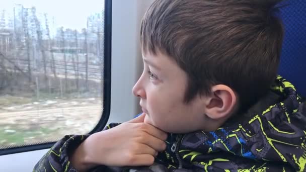 Мальчик едет поездом, он смотрит в окно — стоковое видео