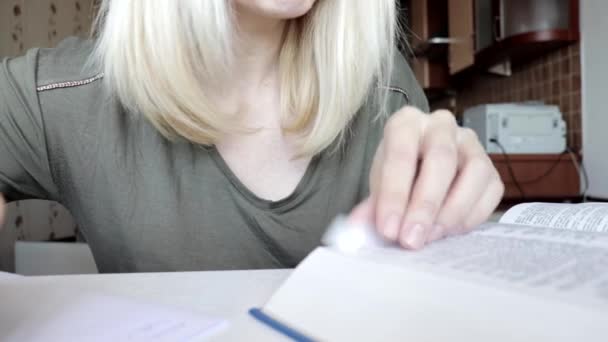 Vrouw bladert door het grote boek, woordenboek en schrijft wat informatie uit, maakt aantekeningen, onderwijs en studentenconcept van dichtbij bekijken — Stockvideo