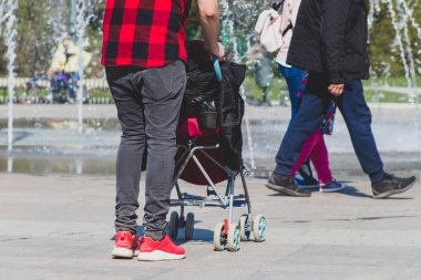 Şehir parkında yürüyen bir bebek arabası ile damalı kırmızı ve siyah gömlek Yalnız tek baba hipster