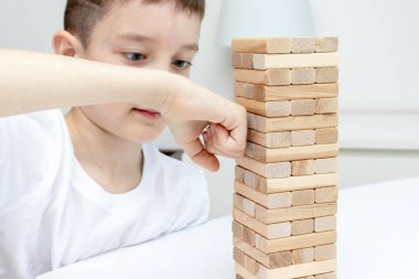 Bir preteen kafkas çocuk kolu ile ahşap blok kule oyunu yumruklama