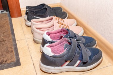 Three pairs of casual shoes - boots, sneakers, running shoes in the hallway clipart