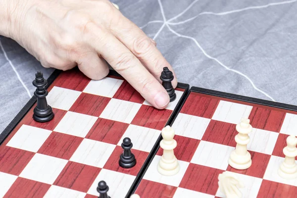 Hand of an elderly senior woman playing chess close up, entertainment and intellectual activity for retired people concept