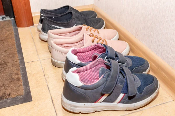 Three pairs of casual shoes - boots, sneakers, running shoes in the hallway