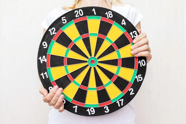 Woman holding a dart board in hands close up, aiming and targetting concept