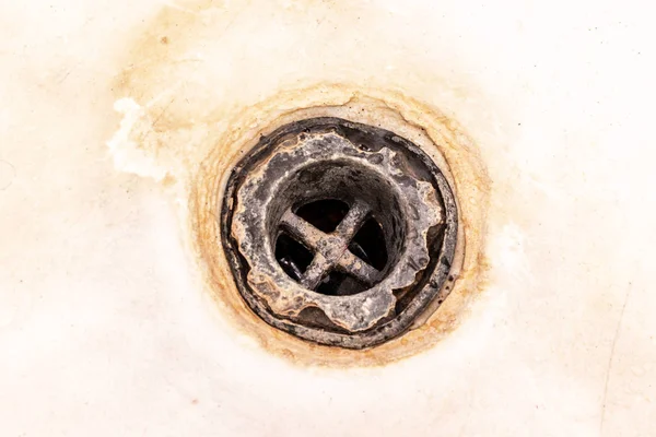 Extremely dirty bath drain mesh, hole covered with limescale or lime scale and rust close up, cleaning calcified and rusty bathroom equipment concept