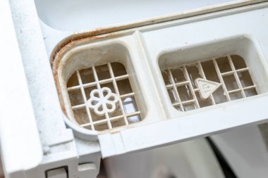 Kirli, küflü çamaşır makinesi deterjanı ve kumaş kremi kutusunun çekmecesini kapat. Küf, pas ve kireç rengi çamaşır makinesi tepsisi. Ev aletleri periyodik bakım