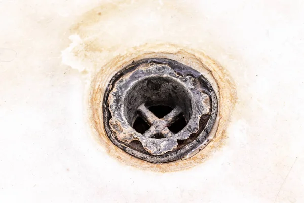 Extremely dirty bath drain mesh, hole covered with limescale or lime scale and rust close up, cleaning calcified and rusty bathroom equipment concept